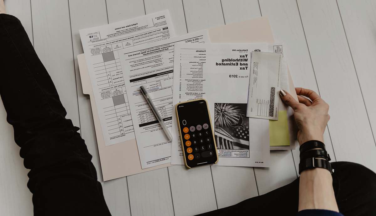 cell phone person holding paper near pen and calculator phone